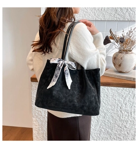 Detail of black textured tote bag featuring elegant black and white patterned silk scarf