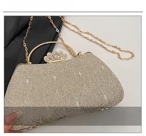 Detailed macro view of champagne gold evening bag with lace fabric and rhinestone crown clasp