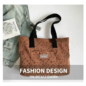 Detail view of corduroy tote bag featuring heart pattern and black strap handles