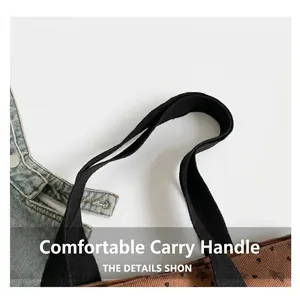 Detail of brown corduroy tote bag showing thick black straps and small heart pattern