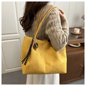 Détail du grand sac cabas jaune avec de longues franges sur une matière mate douce