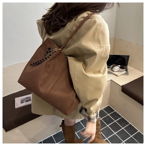 Detail of dark brown suede tote bag featuring retro floral pendant and slim shoulder strap