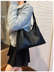 Close-up of sleek black semi-moon leather tote bag showing fine stitching and smooth finish