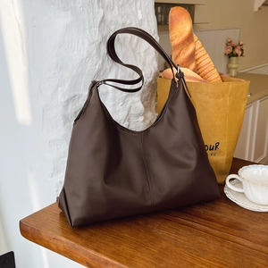 Détail d'un grand sac hobo marron vintage à côté d'un café et de pain dans un café