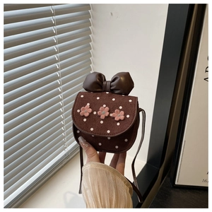 Close-up of brown suede girls crossbody bag with pink flowers and polka dot pattern