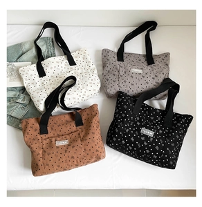 Flat lay of corduroy tote bags with heart and bow patterns in four different colors
