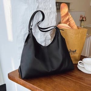 Grand sac fourre-tout noir minimaliste sur table en bois dans un décor de café