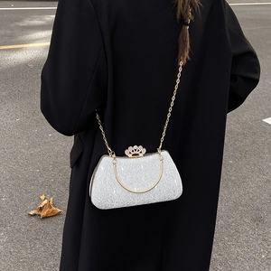 Elegant silver sequin box clutch with crown lock and chain strap on a black coat