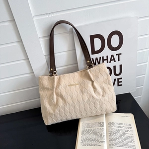 Detail of cream quilted tote bag with retro diamond stitching and brown leather strap
