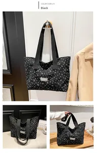 Macro view of black canvas tote bag featuring white heart and bow print with fashion label