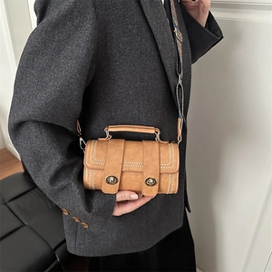 Brown PU leather barrel crossbody bag with patterned strap on a grey blazer outfit