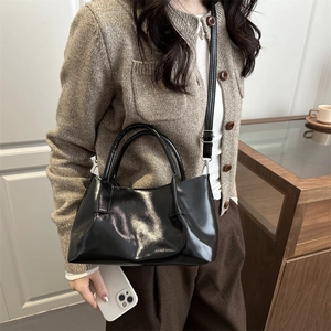 Minimalist black glossy bucket bag for women with dual handles and crossbody strap