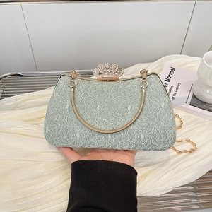 Detail of light green lace evening bag featuring a crystal crown clasp and metal chain