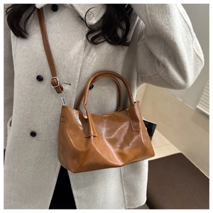 Detail view of a glossy brown PU leather tote with an adjustable shoulder strap and handle