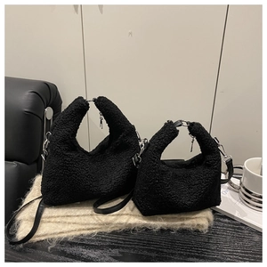 Detail of black plush handbag showing soft faux fur texture and silver metal zipper accents