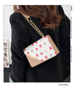 Detail showing printed pattern on small flap crossbody bag with metal chain strap