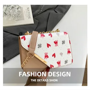 Detail of a chic square bag with bear print and golden chain strap next to a blazer