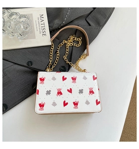 Gros plan du sac bandoulière blanc avec motifs ours et cœur et chaîne en métal doré