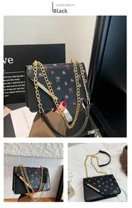 Détails du sac bandoulière en cuir noir avec nœuds roses, motifs floraux et chaîne dorée