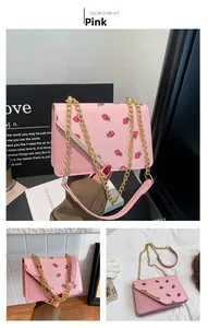 Détail du sac bandoulière rose avec motif fraise et bandoulière en chaîne dorée