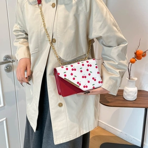 Sac bandoulière tendance hiver 2025 imprimé cerise, cuir rouge et chaîne dorée