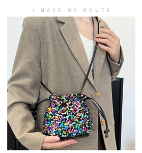 Dettaglio della borsa a secchiello con paillettes colorate su blazer marrone