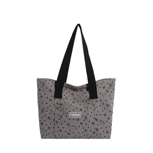 Grey canvas tote bag with black heart and bow prints featuring a functional front pocket