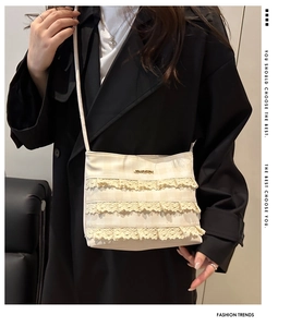 Dettaglio della borsa tote in pizzo crema con bordo floreale su cappotto nero