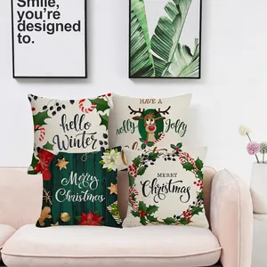 Set of four Christmas pillow covers with reindeer and festive motifs on a pink sofa