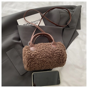 Detailed view of brown teddy fleece cylinder bag with faux leather straps on a grey blazer