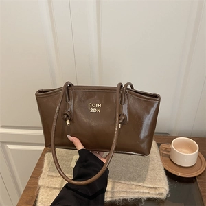 Fashionable dark brown glossy leather tote bag with gold metal logo for urban commuting