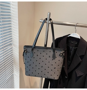 Close-up of gray tote bag with black polka dots and side drawstring detail on a rack