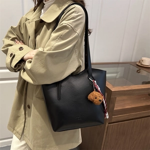 Grand sac cabas en cuir noir avec breloque ours en peluche dans un cadre lifestyle