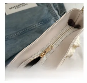 Dettaglio della cerniera dorata e del bordo in pizzo sulla borsa a secchiello beige