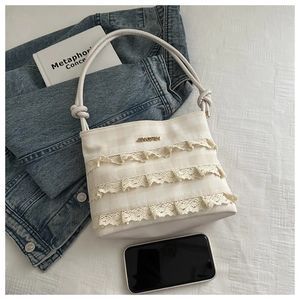 Close-up of cream lace trimmings and textured plaid pattern on this stylish bucket bag