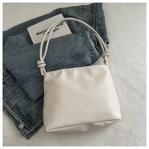Close-up of minimalist beige tote bag with unique knot detail on the shoulder strap