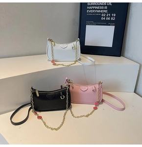 Three half-moon crossbody bags in white, black and pink with strawberry charms