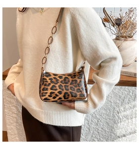 Detail of leopard print glossy shoulder bag with amber resin chain strap on a model