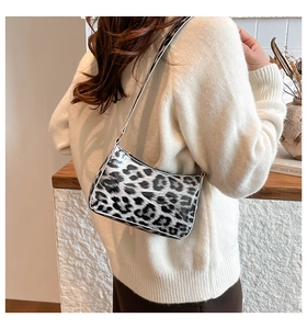 Detail of black and white leopard print hobo bag with gold zipper and narrow shoulder strap