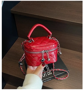 Close-up of red quilted box bag with silver chain strap and heart-shaped zipper pull