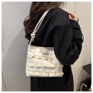 Dettaglio di una borsa tote crema trendy con volant in pizzo e logo in metallo