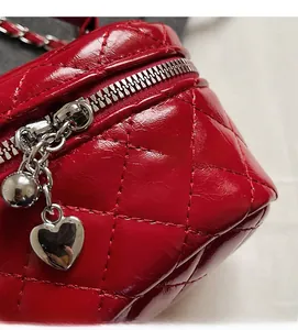 Macro shot of red quilted faux leather bag with heart pendant and chain strap