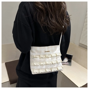 Close-up of a cream plaid crossbody bag featuring elegant triple-layer lace trim and metal logo