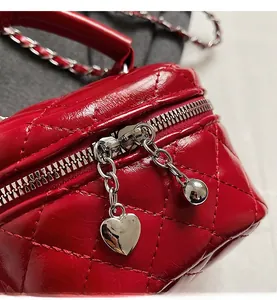 Close-up of red quilted leather mini bag featuring heart and ball metal zipper charms