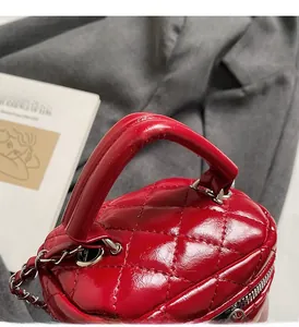 Detail of red quilted leather mini box bag with sturdy handle and silver chain strap