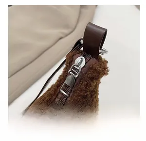 Detailed close-up of dark brown plush texture and smooth silver metal zipper on the bag