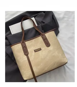Detail view of khaki suede tote bag with brown straps and brand logo patch