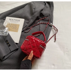 Détail d'un mini sac cylindrique rouge matelassé avec bandoulière chaîne argentée