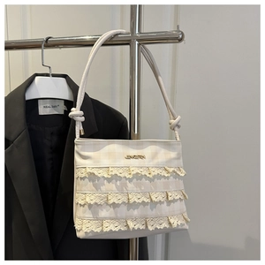 Detail of white lace layers and golden logo on the textured plaid crossbody bag