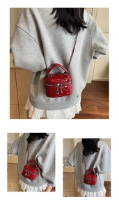 Detail of red quilted mini bag with silver chain strap and heart zipper pulls
